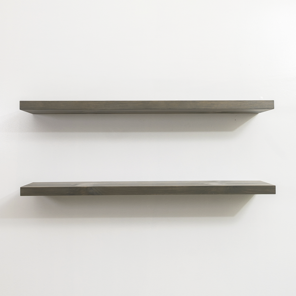 Two gray wooden floating shelves on a white wall