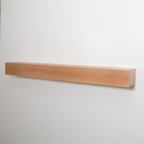 A long, minimalist floating wooden fireplace mantel in a light natural oak finish, mounted on a plain white wall.