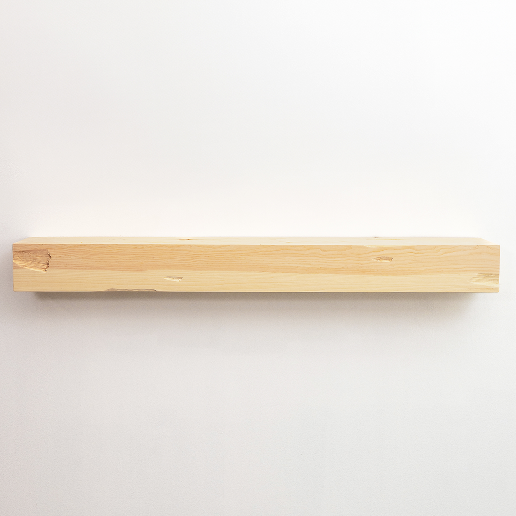 A minimalist, natural light wood floating fireplace mantel mounted on a plain white wall.