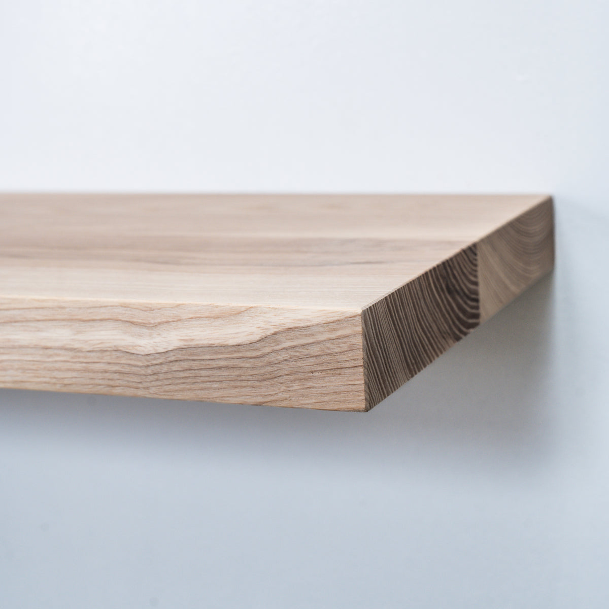 Wooden unfinished ash floating shelf with a visible grain on a light gray background