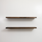 Two wooden floating shelves on a white wall
