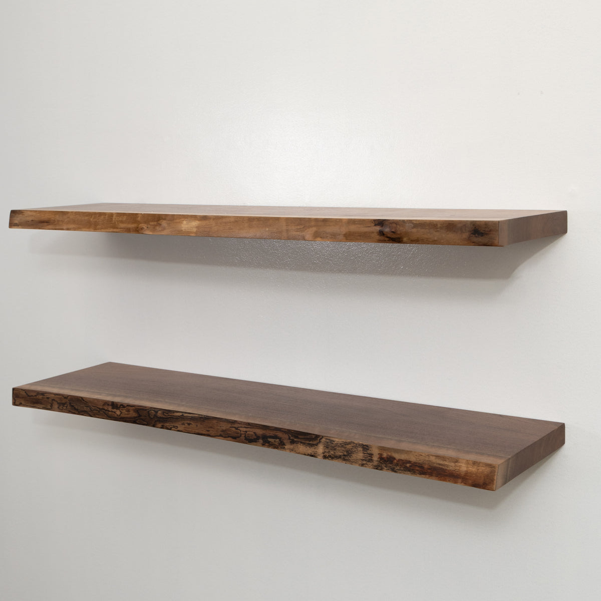 Two wooden floating shelves on a white wall