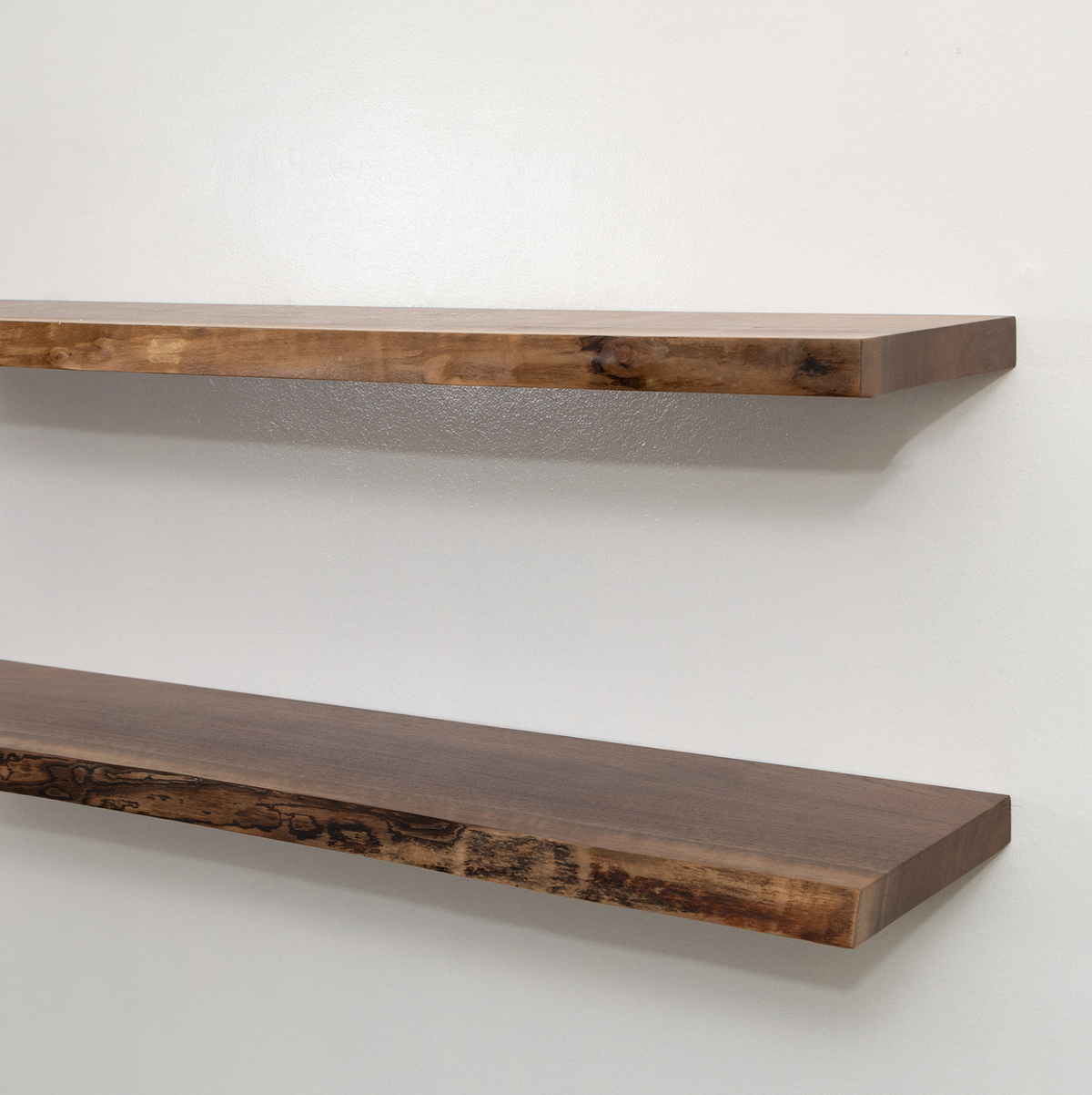 Two wooden floating shelves on a white wall