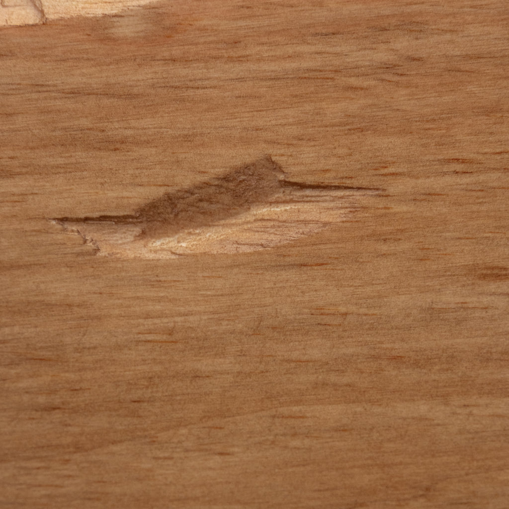 A close-up of a light brown wood surface with visible grain and a small natural defect or knot near the center.