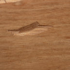 A close-up of a light brown wood surface with visible grain and a small natural defect or knot near the center.