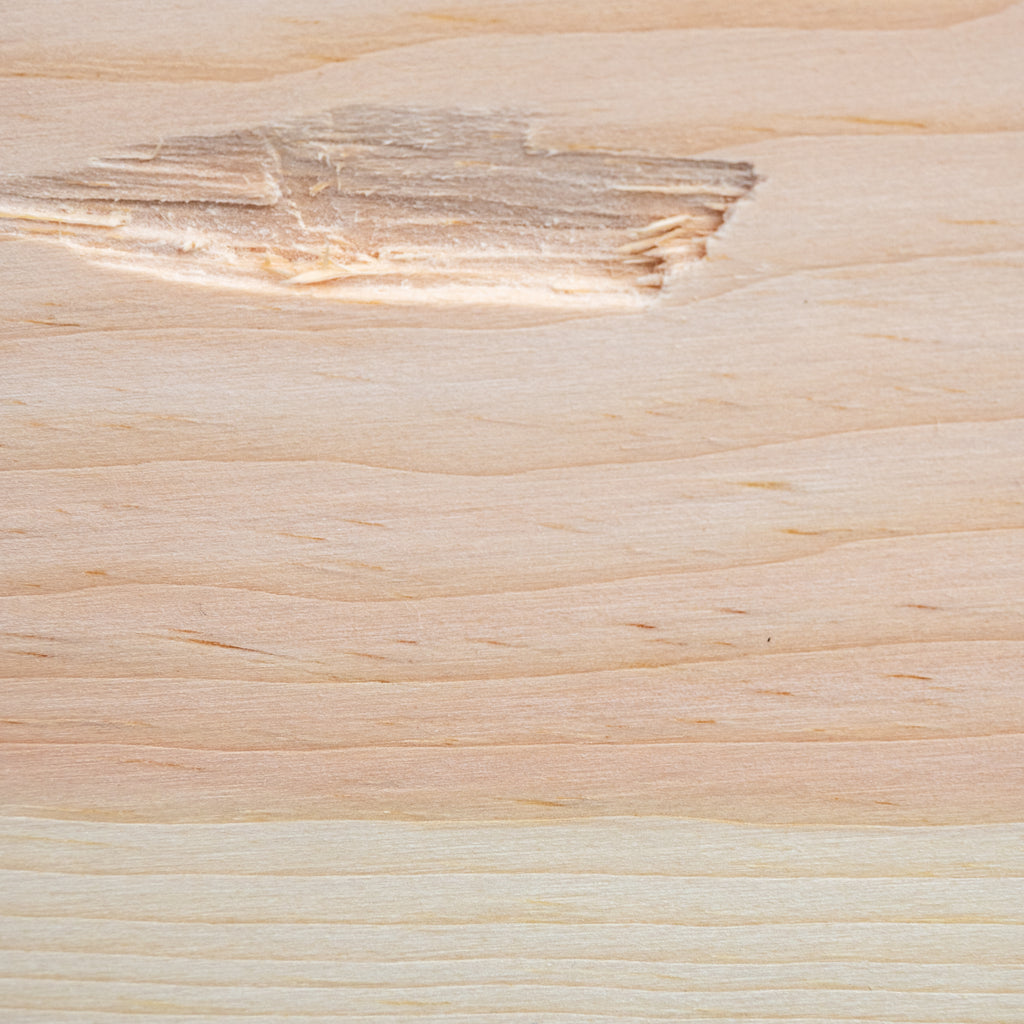 A close-up of a light natural wood surface with visible grain, knots, and a slightly rougher patch near the top left.
