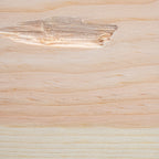 A close-up of a light natural wood surface with visible grain, knots, and a slightly rougher patch near the top left.