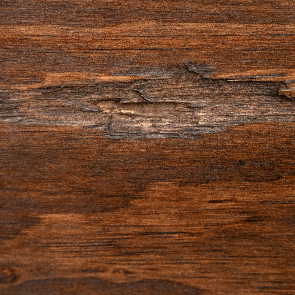 A close-up of a dark brown wood grain surface with visible natural texture, knots, and linear grain patterns.