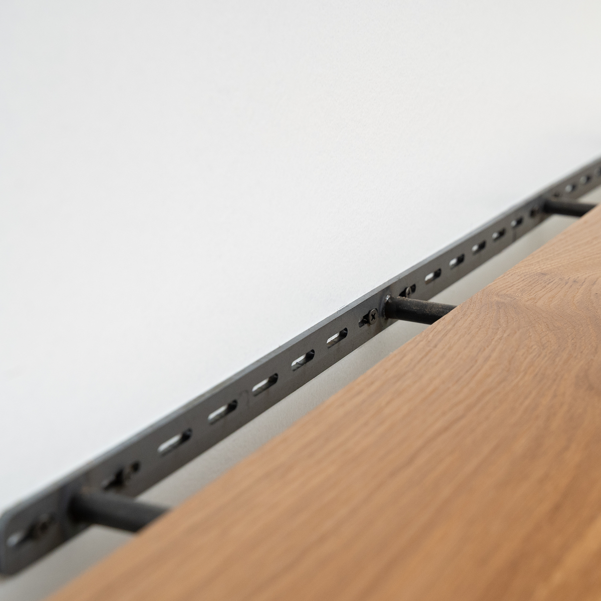 Metal floating bracket installed on a white wall