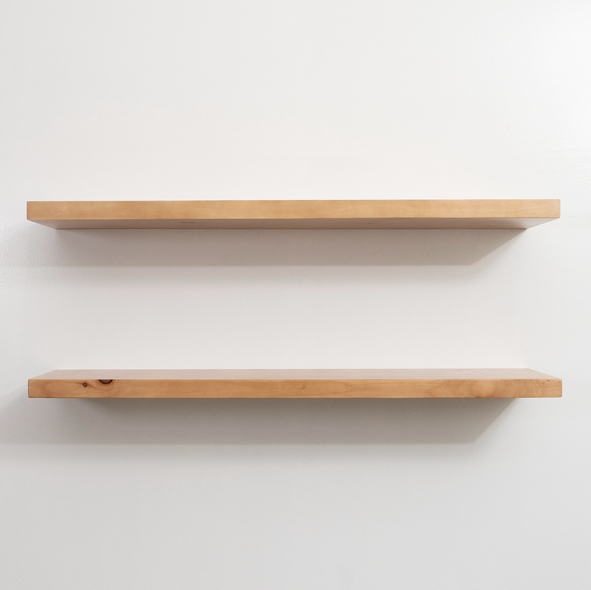 Two wooden shelves on a white wall
