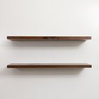 Two wooden floating shelves on a white wall
