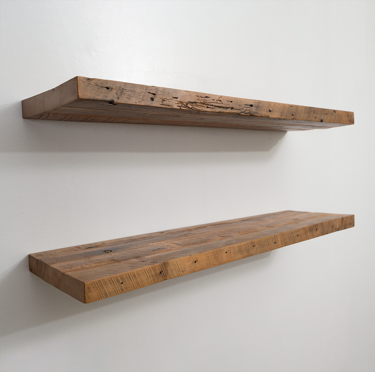 Two reclaimed wood floating shelves on a white wall