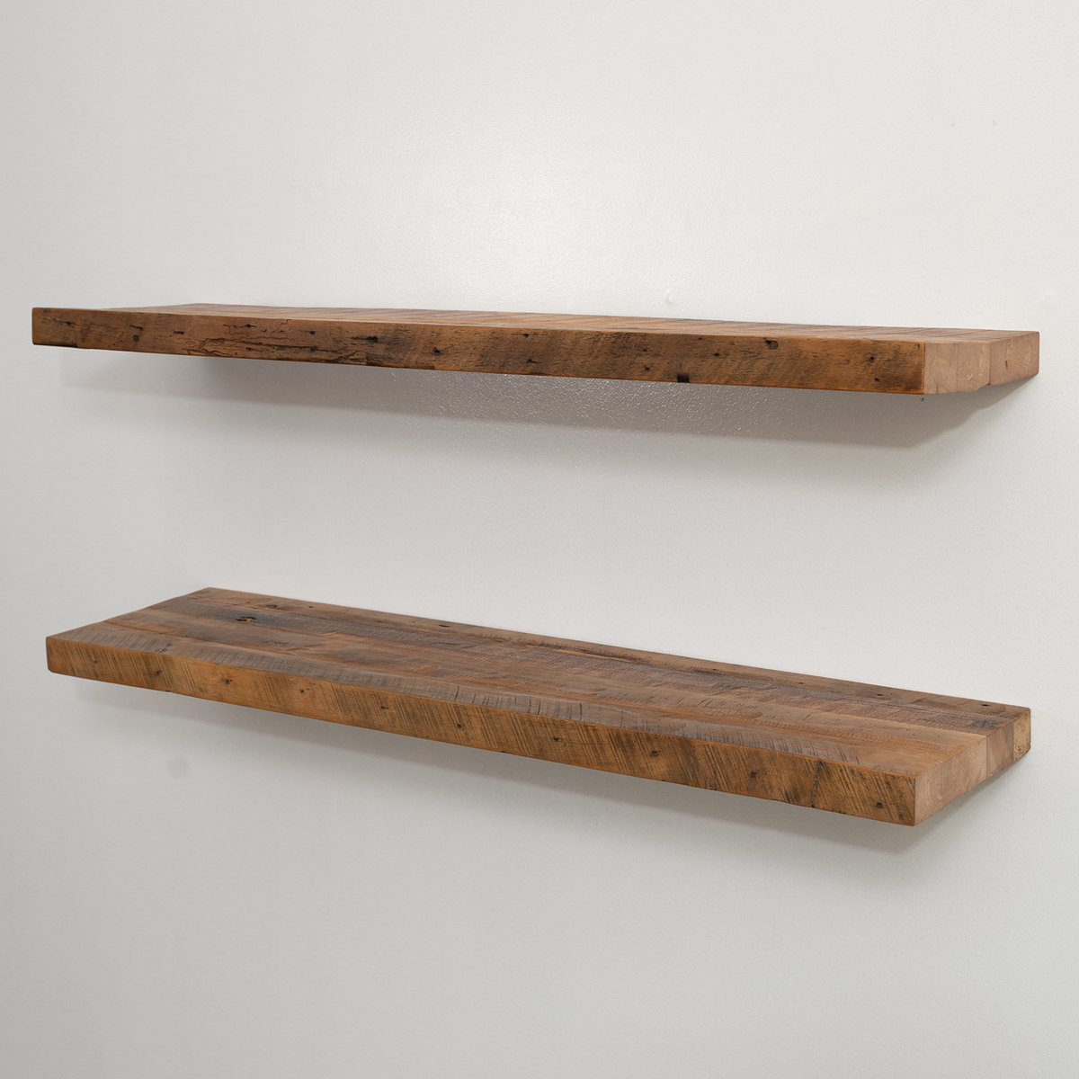 Two reclaimed wooden floating shelves on a white wall