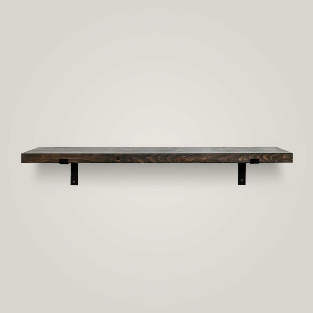 A minimalist floating wooden shelf with a dark gray finish and two black metal brackets, mounted on a plain white wall.