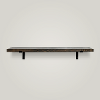 A minimalist floating wooden shelf with a dark gray finish and two black metal brackets, mounted on a plain white wall.