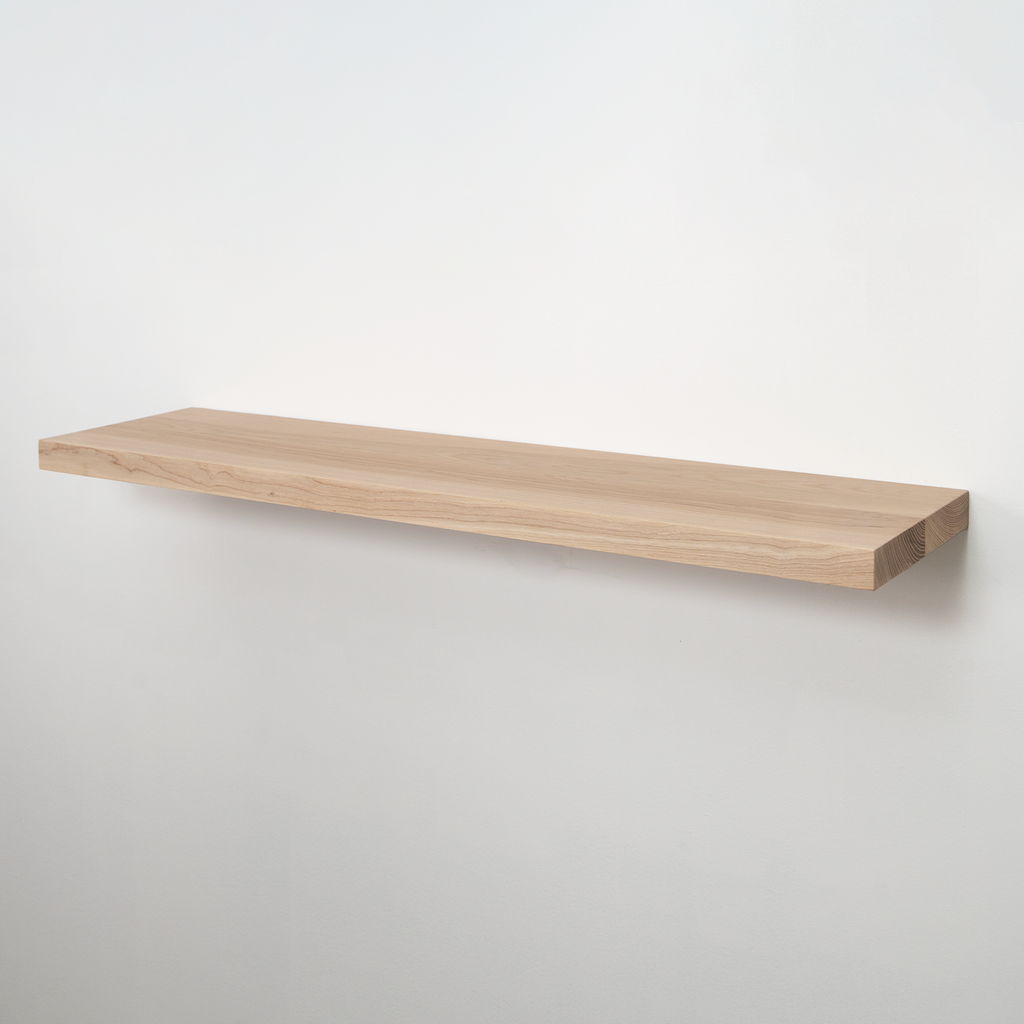 A minimalist floating wooden shelf with a natural light oak finish, mounted on a plain white wall.