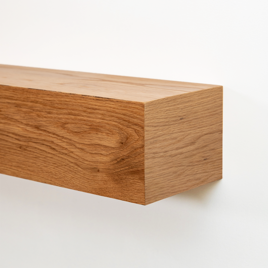 Close-up of a floating wooden fireplace mantel made of warm medium-brown wood with visible grain, mounted against a plain white wall.