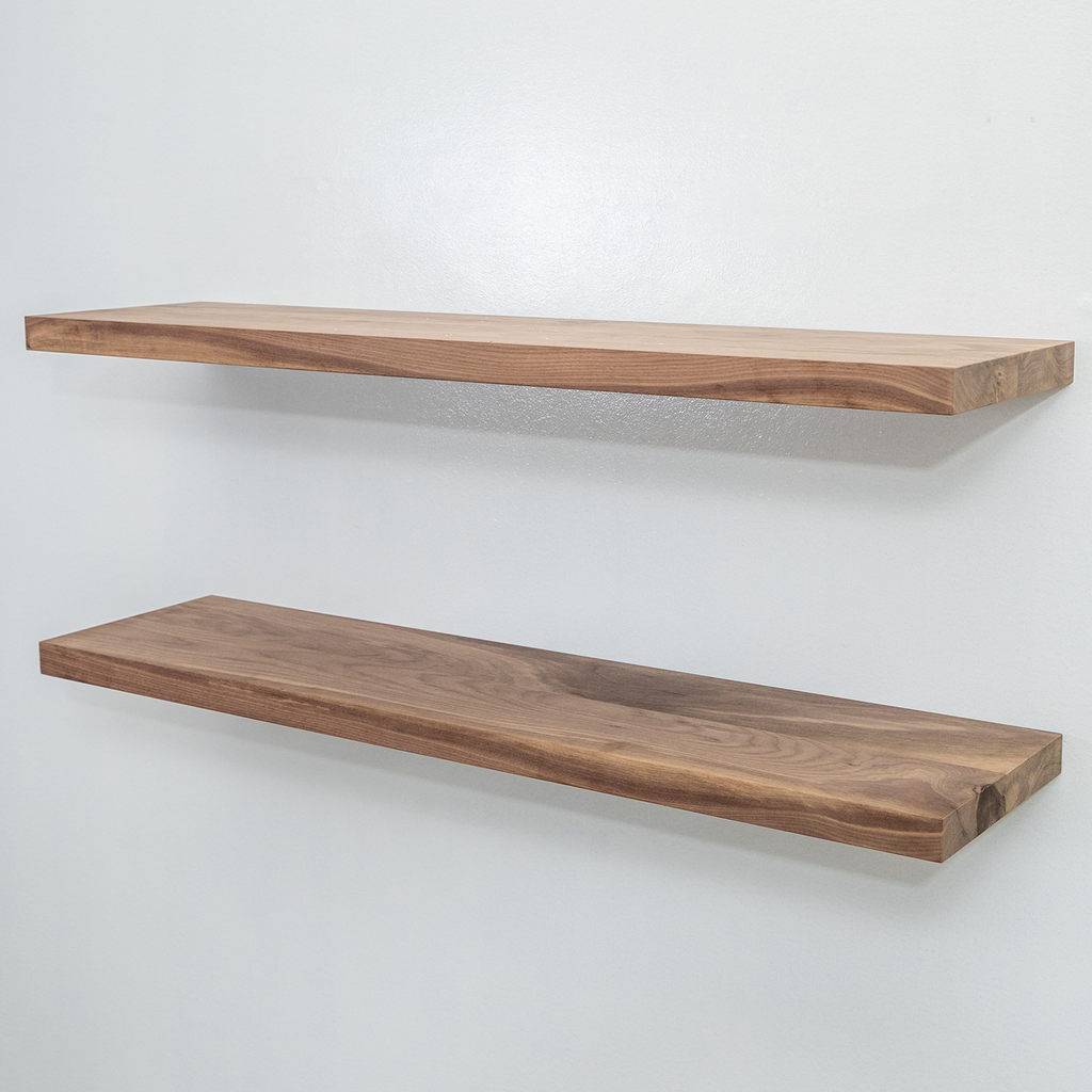 Two wooden unfinished walnut floating shelves on a white wall