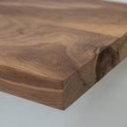 Close-up of a wooden floating shelf with a natural grain pattern on a light gray background