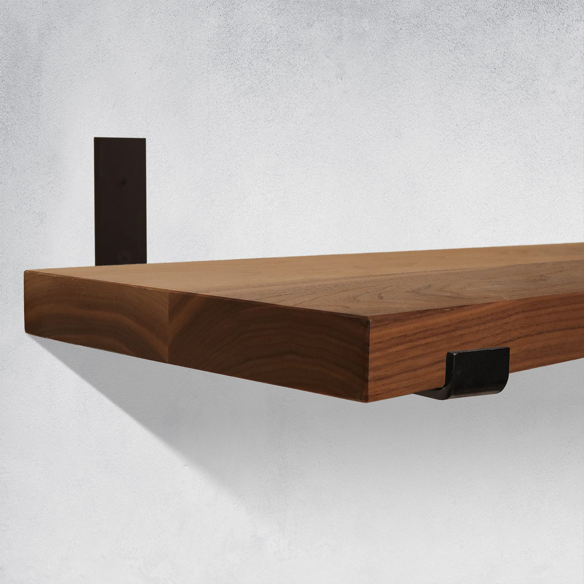 Wooden shelf with black brackets on a light gray background