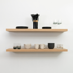 Wooden white oak floating shelves with kitchenware on a white wall