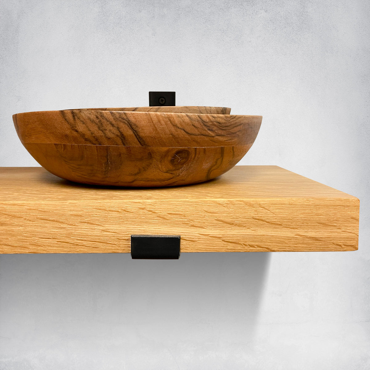 Wooden bowl on a wooden shelf against a gray background