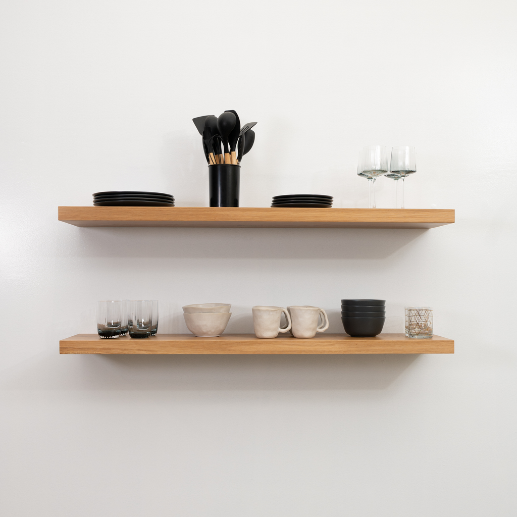 Wooden white oak floating shelves with kitchenware on a white wall