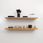 Wooden white oak floating shelves with kitchenware on a white wall
