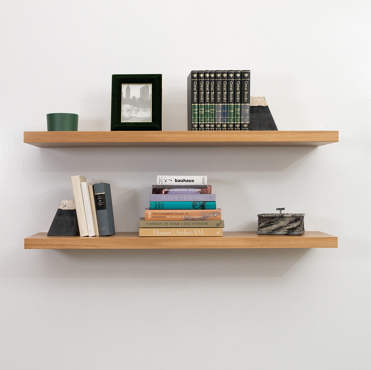 Wooden white oak floating shelves with books and decorative items against a white wall