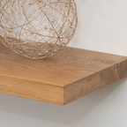 Wooden white oak floating shelf with a decorative spherical object on a plain background