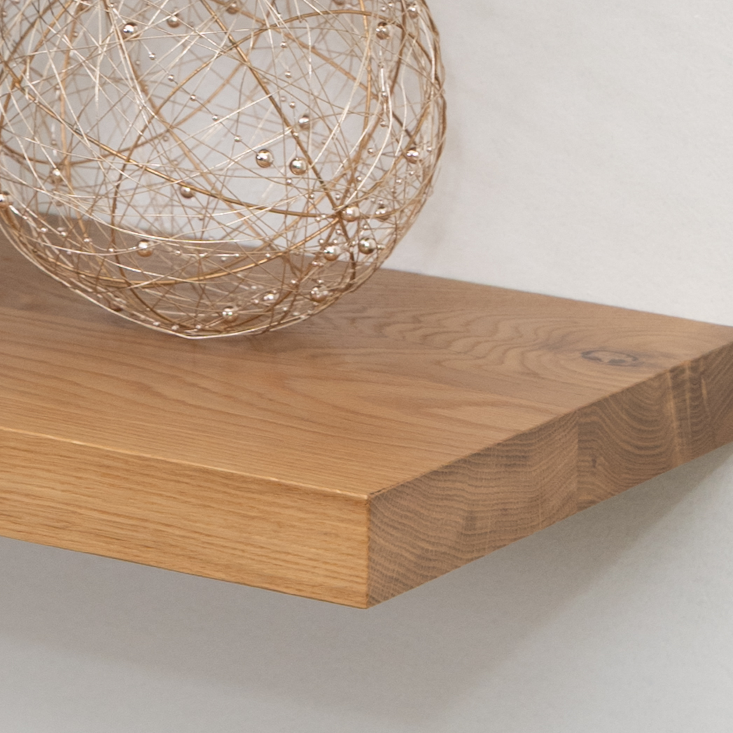 Wooden white oak floating shelf with a decorative spherical object on a plain background