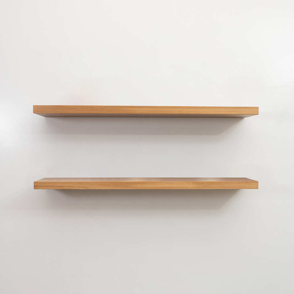 Two wooden floating shelves on a white wall