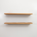 Two wooden floating shelves on a white wall