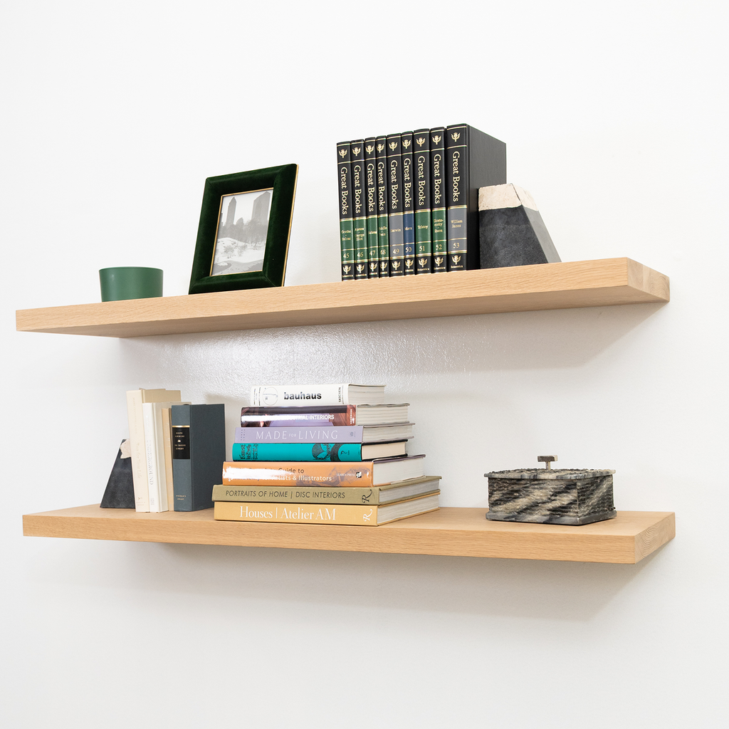 Wooden white oak floating shelves with books and decorative items against a white wall