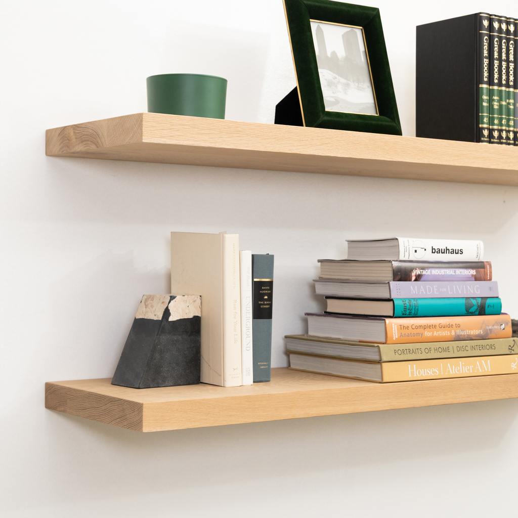 Wooden floating shelves with books and a picture frame on a white wall