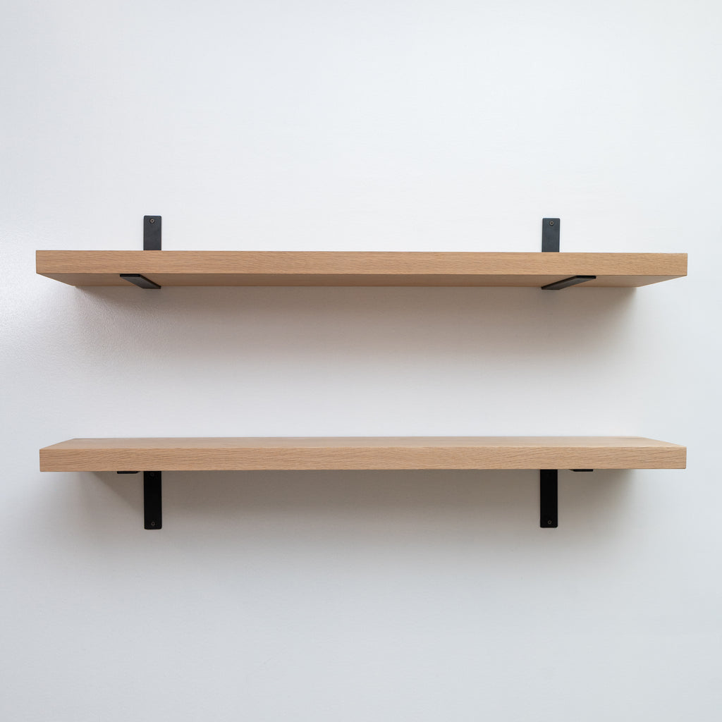 Two wooden shelves with black brackets on a white wall