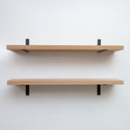 Two wooden shelves with black brackets on a white wall