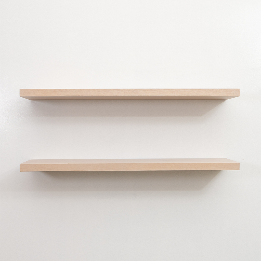 Two wooden floating shelves on a white wall