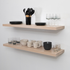 Wooden shelves with kitchenware including plates, cups, and utensils against a white wall.