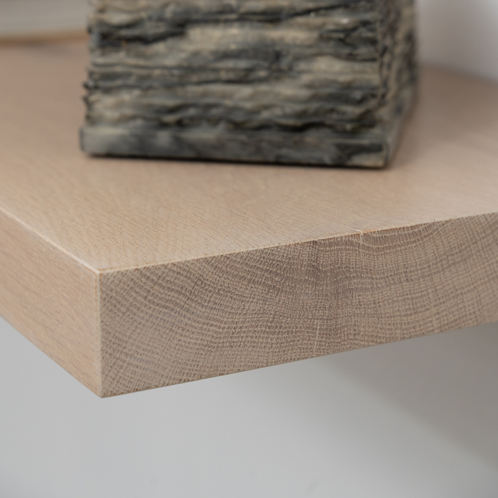 Close-up of a wooden floating shelf with a stone sculpture on a neutral background