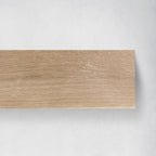 A rectangular wood fireplace mantel with a light oak grain pattern, shown against a neutral light gray textured background.